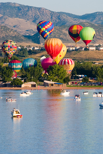 Collage of hot air ballons ascends from the lake front while boats look on.