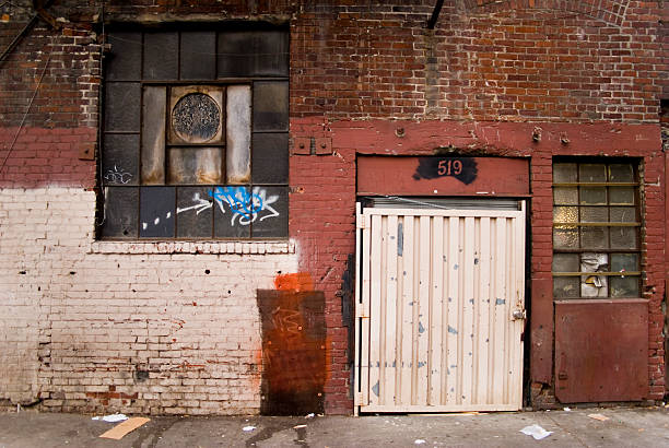 Dirty red brick alley View of the back of a building in an alley. graffiti brick wall dirty wall stock pictures, royalty-free photos & images