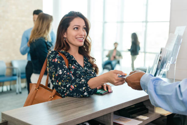 Woman hands her debit card to the bank teller stock photo