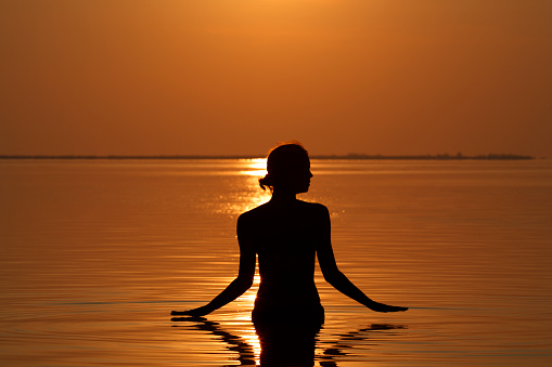silhouette of a woman taking a dip in the ocean at sunset