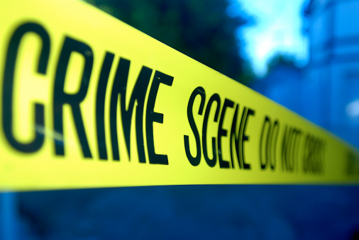 Close-up on yellow crime scene tape over blue abstract background.