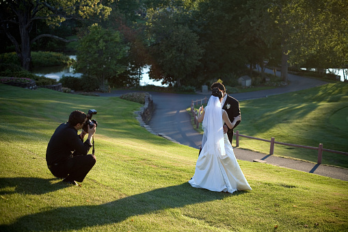 Photographer trying to photograph a wedding couple outdoors on the landscape