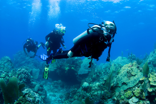 A scuba diving tank and gear standing on a boat bow with blue sea and sunshine as a banner with copy space