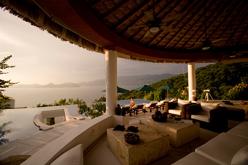 An open air villa with an infinity pool and a view looking out to the ocean during sunset in Acapulco Mexico.