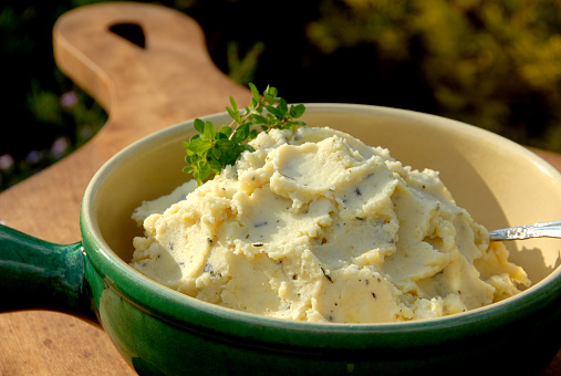 Mashed Yukon Gold potatoes garnished with thyme leaves and cracked pepper