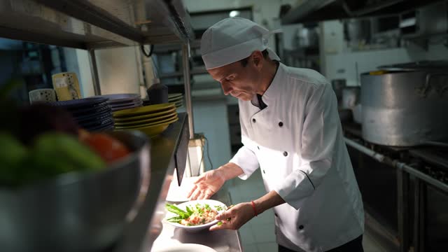 Head chef finishing to prepare a dish in a commercial kitchen