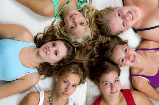 high angle shot of 6 teenage girls lying on white cushions