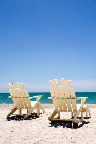 Two empty beach chairs overlooking a beautiful turquoise ocean. 
