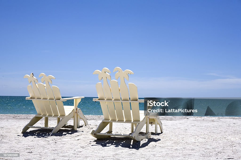 Back of two white wooden chairs on sand with ocean Two white beach chairs on white sand overlooking a turquoise sea. http://i191.photobucket.com/albums/z193/LattaPictures/Sanibel_Beachchairs-0055_Series.jpg  Florida - US State Stock Photo