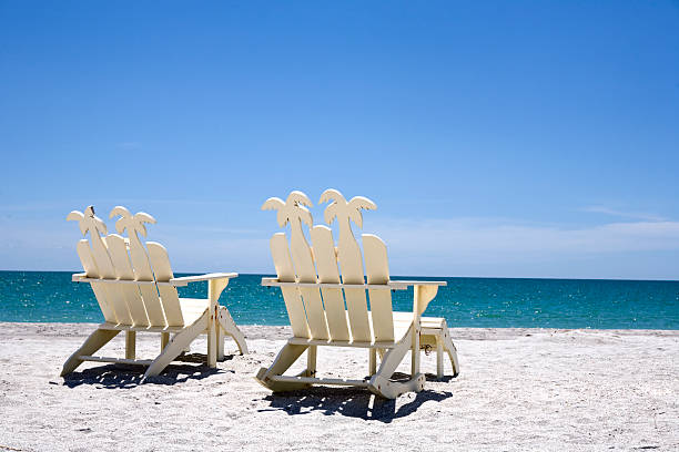 Back of two white wooden chairs on sand with ocean Two white beach chairs on white sand overlooking a turquoise sea. http://i191.photobucket.com/albums/z193/LattaPictures/Sanibel_Beachchairs-0055_Series.jpg  fort myers photos stock pictures, royalty-free photos & images