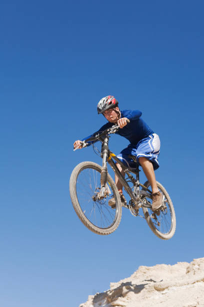 Cyclist on mountain bike jumping of a cliff stock photo