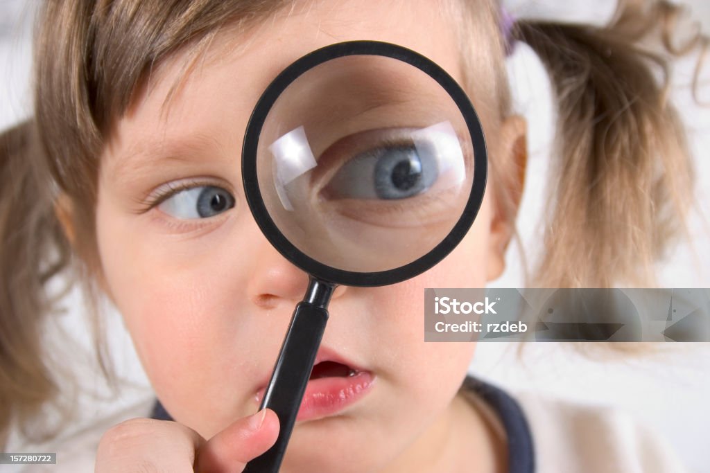 Searching ... Little girl with magnifier Humor Stock Photo