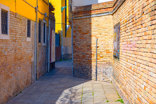 Colorful narrow street in old city of Venice, Italy . Old red brick architecture