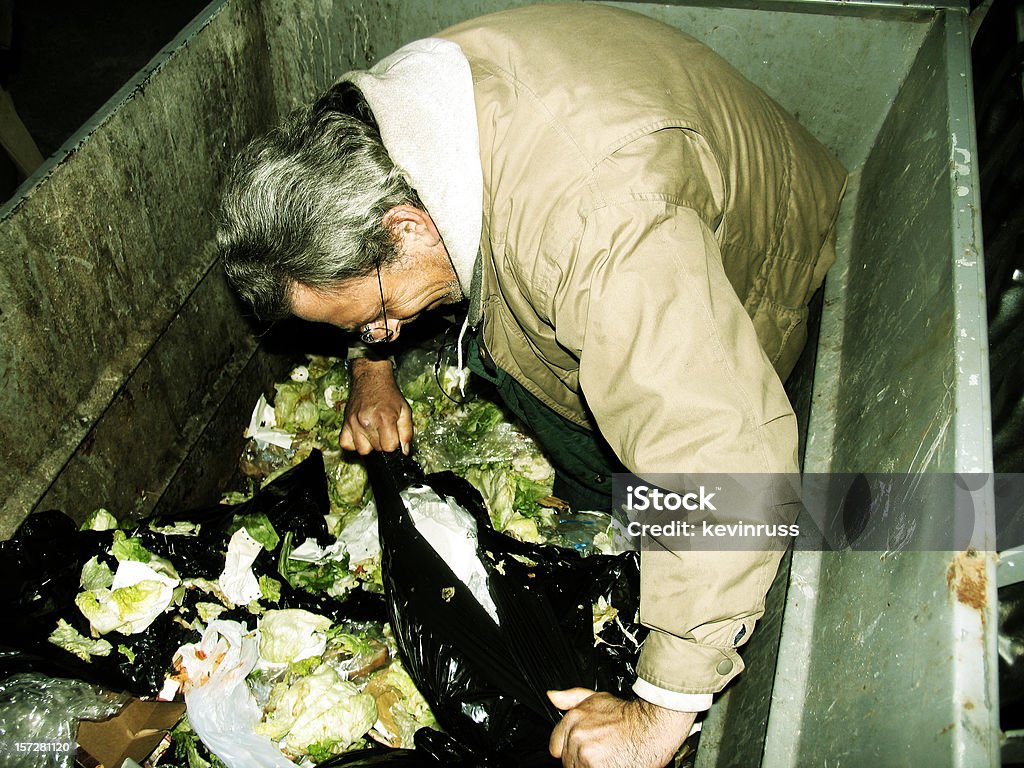 Homme sans-abri dans la benne à ordures - Photo de Benne à ordures libre de droits