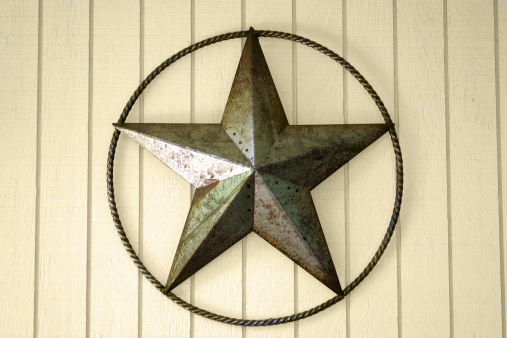 Star encircled by rope made of rusted,grungy sheet metal on textured background.