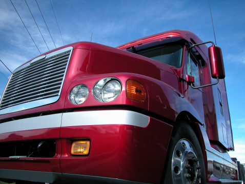 new red semi truck set against blue sky