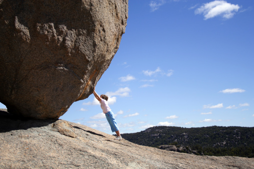 Young woman standing on the rock  facing the rocky mountain