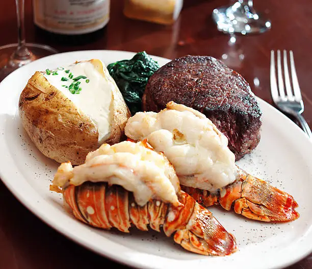 Lobster tails, fillet mignon and baked potato with spinach.