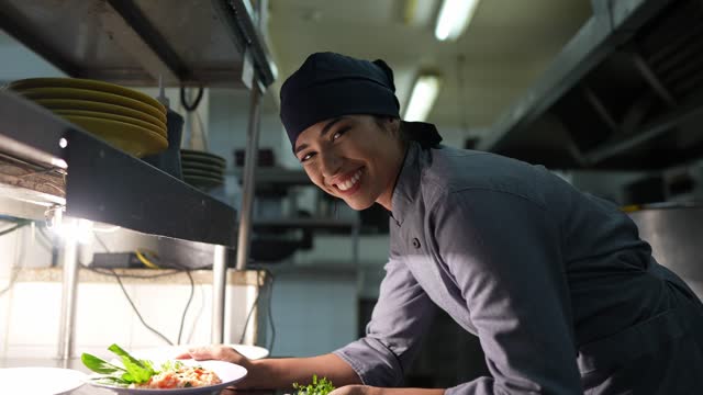 Portrait of a happy chef finishing to prepare a dish in a commercial kitchen