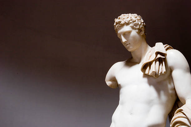 A beige roman statue on a gray background. stock photo