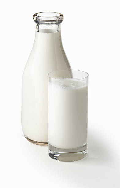 Milk Quart bottle of milk with glass of milk shot on clean white background with soft drop shadow.  Large file includes path. milk bottle stock pictures, royalty-free photos & images