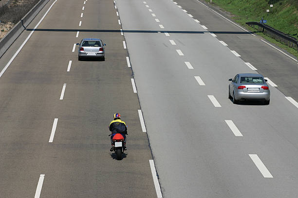 Some cars and motorbikes on the highway from the back.