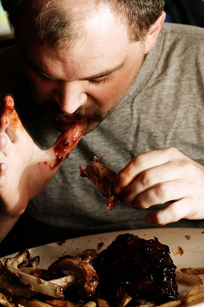 Jovem comer Desarrumado costelas - fotografia de stock