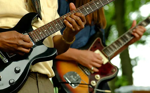 Photo of Close up of two people playing guitars