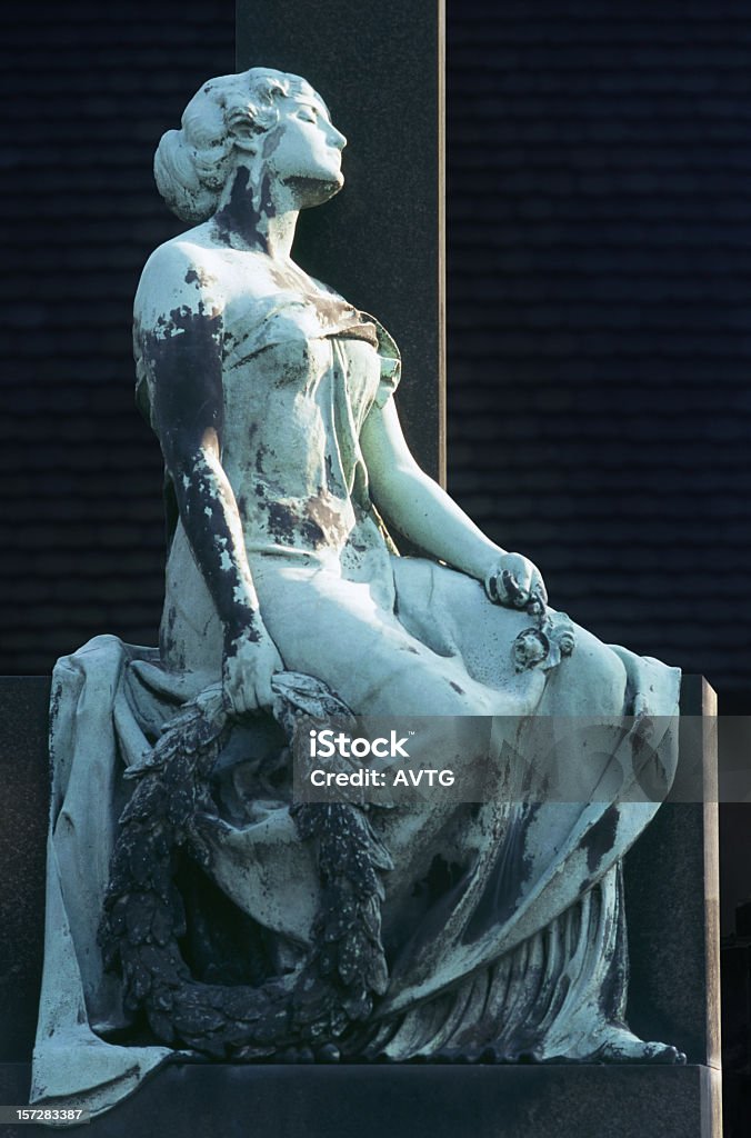 Remembrance On a cemetary, statue leaning to a cross Pain Stock Photo