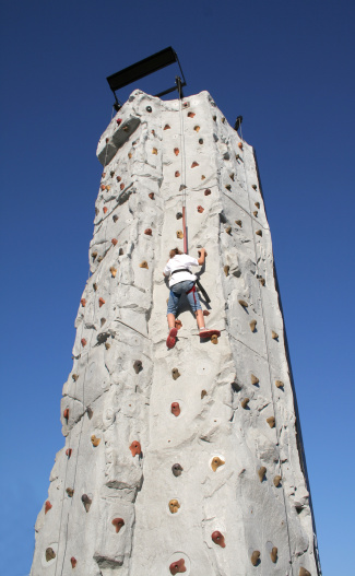 teenage boy climbing up the wall in outdoor adventure park passing obstacle course. high rope park