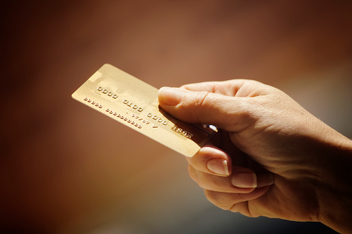 Hand holding a gold credit card.