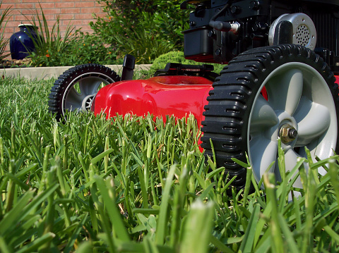 Macro front view of a brand new red lawnmower. Focus center fading slightly outward.