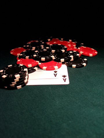 Pocket Aces on green felt with black and red chips