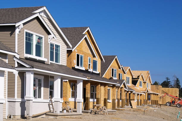 Housing Development Under Construction Perspective photo of a row of similar style houses during various phases of construction. foundation stock pictures, royalty-free photos & images