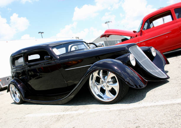 Black antique model car with red car next to it 