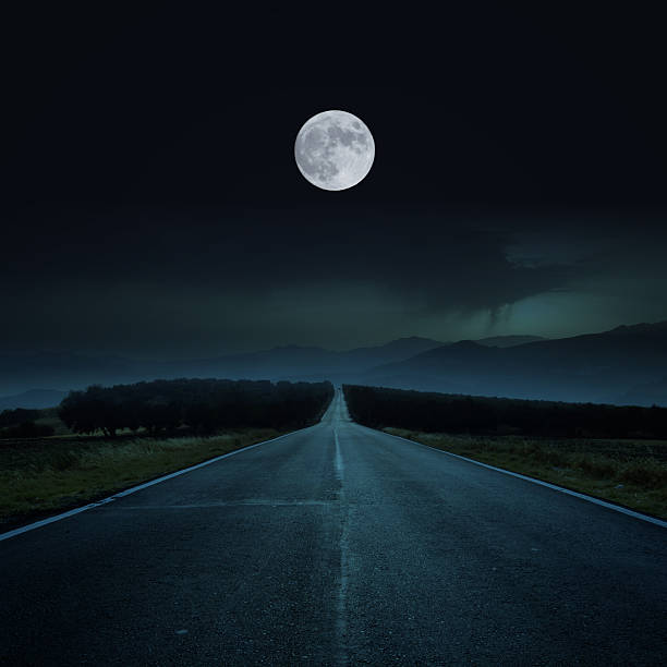 Road by night A long and direct road to the moon. dark street stock pictures, royalty-free photos & images