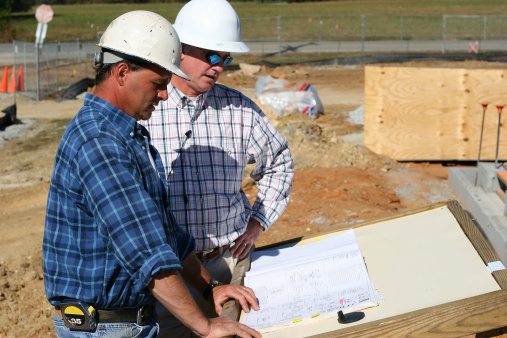 Two construction workers reviewing blueprints