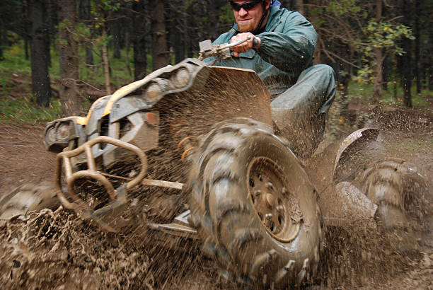 Man in mud on quad A quad coming out of the mud with lots of mud spray. quadbike photos stock pictures, royalty-free photos & images