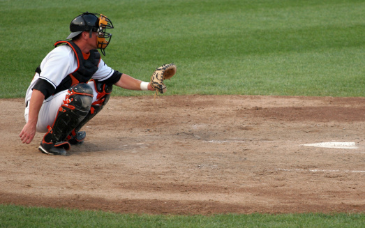 professional baseball catcher crouches behind home plate ready to catch a pitch 