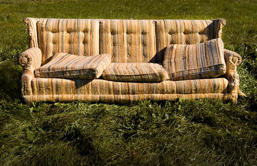 Old warn sofa on grass lawn