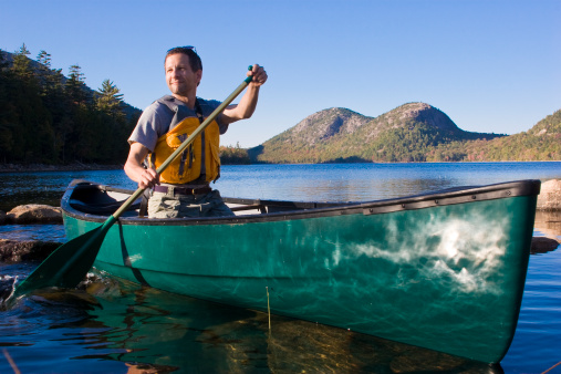 Canoeing in Jordan Pond, Acadia National Park, Maine. The double-hump mountains behind the canoeist are called 