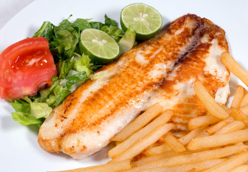 homemade white fillet of fish sauteed with fries and salad close up