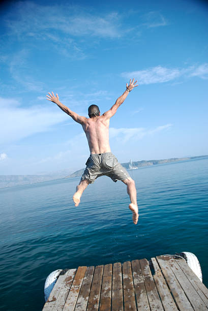 istock Man Jumping from Dock into Blue Sea Water 157287186
