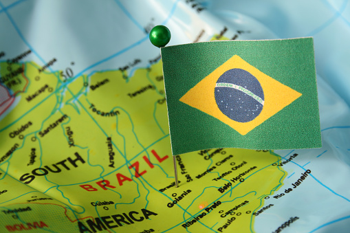Brazilian flag over cheap plastic map pointing Brasilia