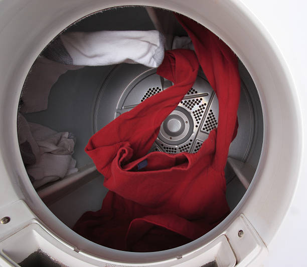 Clothes Tumbling in Dryer A red shirt and several socks tumble through the air inside a dryer. Light motion blur on the moving clothes. dryer stock pictures, royalty-free photos & images