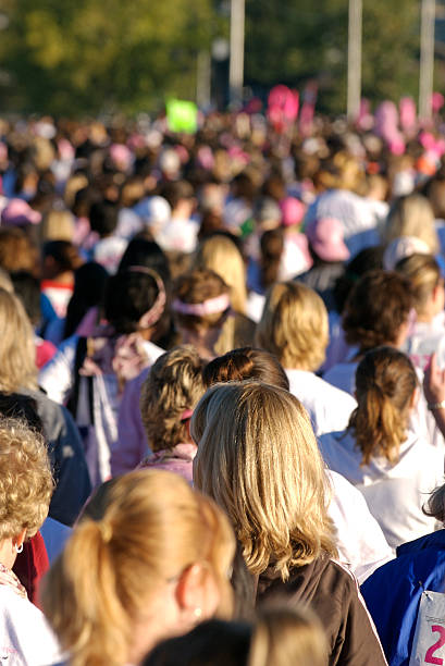 A large group of women wearing pink Some of the 26,000 women who participate in the Susan G. Komen Race for the Cure in Little Rock, Arkansas, to raise money to fight breast cancer. walking for a cause stock pictures, royalty-free photos & images