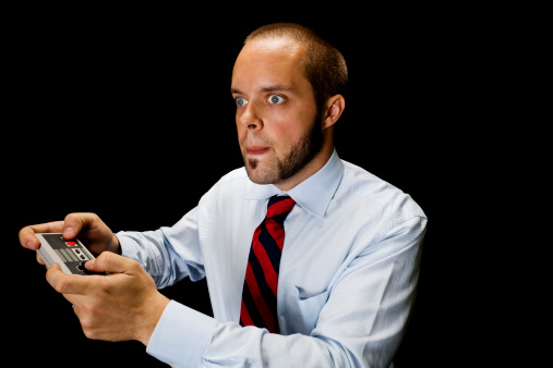 Man in business attire playing games with an inquisitive look on his face. 