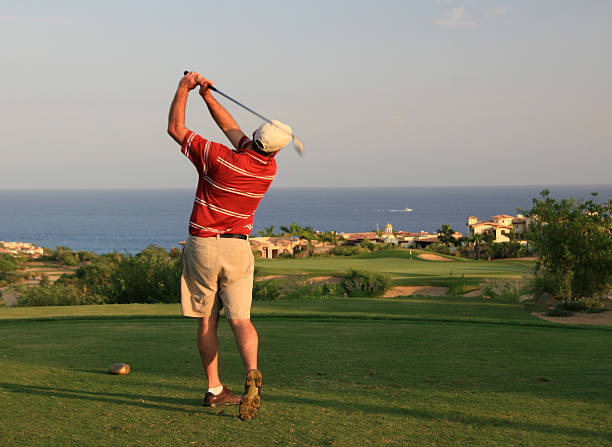 Male Caucasian Golfer Swinging in Mexico On the tee at a beautiful golf course by the ocean in Cabo San Lucas,Mexico. Rear view of athletic male Caucasian golfer on a seaside course. Cabo is one of the world's great golf destinations with over a dozen golf courses, many designed by Jack Nicklaus. game resort pictures stock pictures, royalty-free photos & images