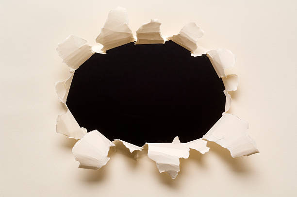 istock Ripped hole in a paper withblack background 157288595
