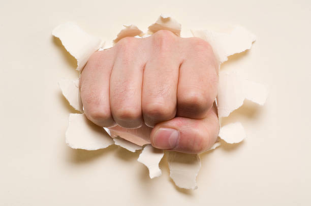 istock Fist punching through a ripped hole in a paper 157288670